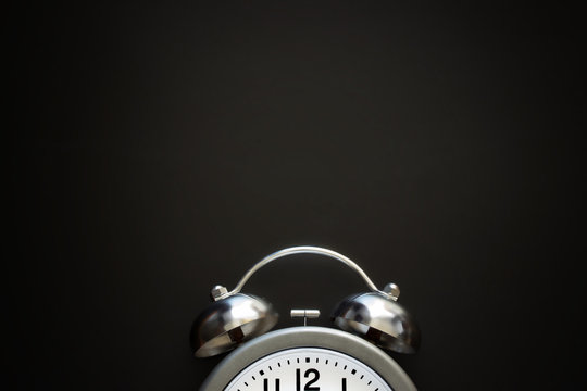 Classic alarm clock with bells and arrows on background from black chalkboard. Top view. Close up. Flat lay. Mockup