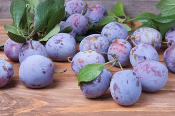 plums with leaves on the wooden background