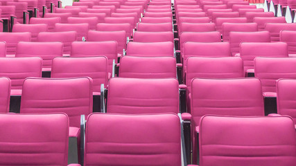 Red seat rows in a bright lecture room.