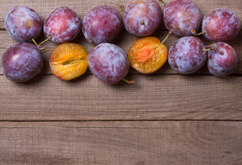 frame of plums on the old wooden background