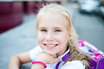 Fototapeta na wymiar Little beautiful smiling girl on a background city street.