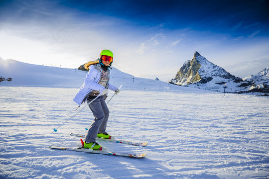 Teenager girl skiing on ski slope with Matterhorn in background in sunny day. Zermatt, Switzerland, Wallis region.
