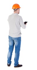 young engineer in a protective helmet with tablet computer in the hands of. Rear view people collection.  backside view of person.  Isolated over white background. Engineer verifies the work done with