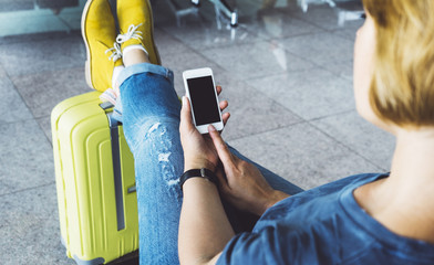 Young hipster girl at airport and put feet in yellow boot on suitcase waiting air flight, female...