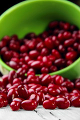 Scattered cornel berries on wooden table from green plate.Selective focus.Focus on rolling beries on the first plan