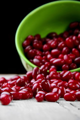 Scattered cornel berries on wooden table from green plate.Selective focus.Focus on rolling beries on the first plan