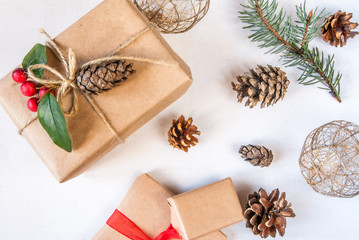 Christmas gifts surrounded by tree branches and pine cones on the light table, top view