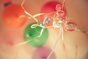 Birthday party background with colourful coiled ribbons and  blurred balloons