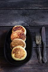 Cottage cheese pancakes on old iron pan. Style rustic. Selective focus. 