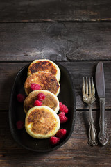 Cottage cheese pancakes with raspberries on old iron pan. Style rustic. Selective focus. 