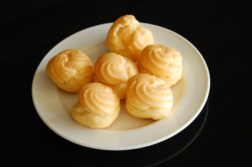 Eclairs or profiterole with chocolate and whipped cream preparing on baking sheet. Spreading chocolate on top of eclair with spoon. Traditional French dessert. Empty space for design text template.