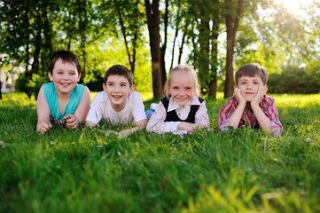 Fototapeta premium four children lie on their stomachs on the grass and smiling