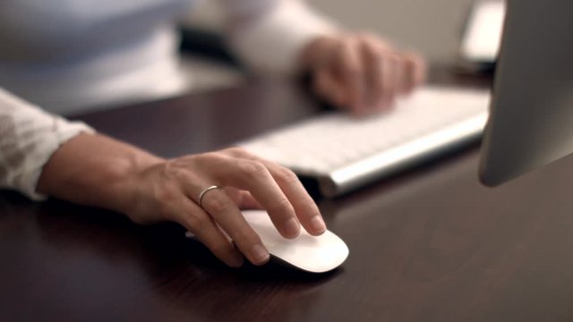 Woman typing on computer at desk in high quality 4k format