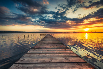 Drewniana kładka nad jeziorem o zachodzie słońca