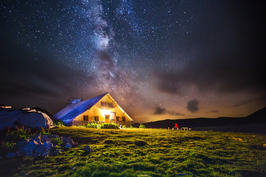 Hut in the mountains at night under the milkyway