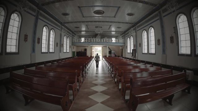 Senior man walking to the light of the entrance of the church.