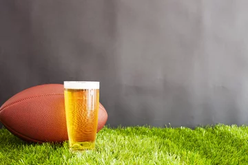Vintage football and beer glass over grass and black background © Andreka Photography