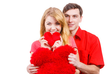 Couple holds red heart shaped pillows love symbol