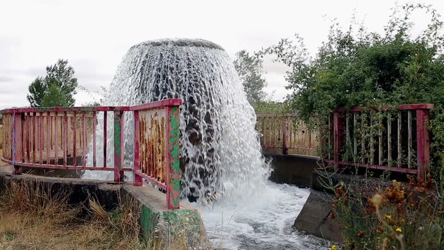 Water gushes from pipe to feed an irrigation watercourse canal