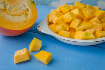 Autumn raw sliced pumpkin on blue wooden background