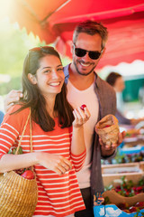 Obraz premium A young couple eating cherries on a market in summer