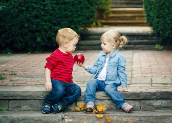 Group portrait of two white Caucasian cute adorable funny children toddlers sitting together sharing apple food, love friendship childhood concept, best friends forever - Powered by Adobe