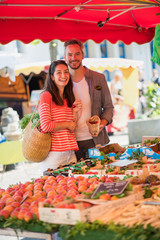 A young couple eating cherries on a market in summer