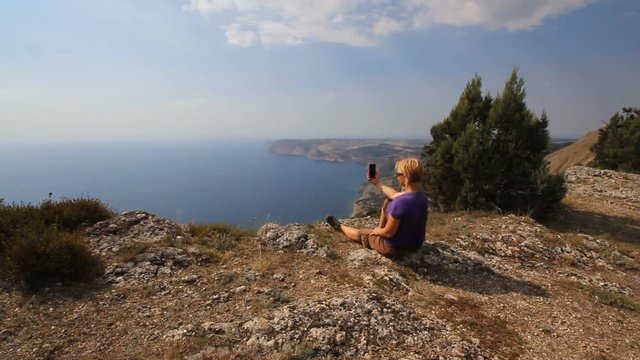 traveler woman resting on the top of a mountain with a mobile phone
