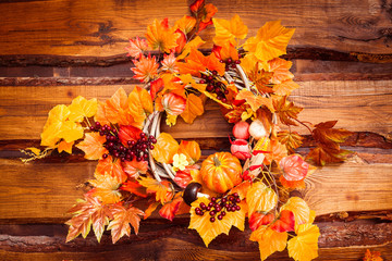 Obraz premium Woven wreath decorated orange leaves, autumn vegetables