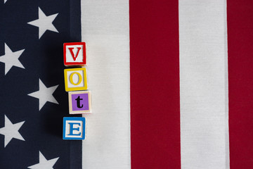 Fototapeta na wymiar Vote! The word vote spelled out in letter blocks on top of an American flag. 
