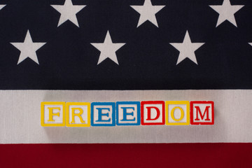 American freedom!  The word freedom spelled out on letter blocks on top of an American flag.  