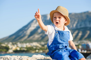 Cute blond boy in hat and blue overall