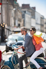A trendy couple doing sales on a vintage scooter in the city