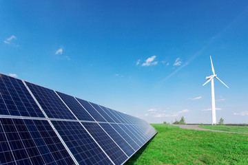 Windmill and solar panels on blue sky at daytime