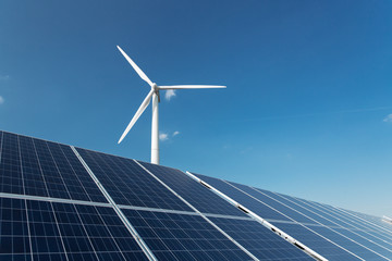 Windmill and solar panels on blue sky at daytime