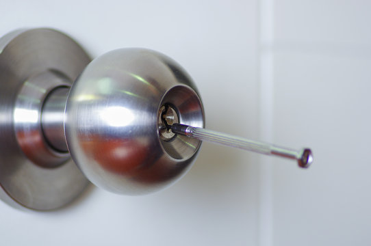 Closeup hands of locksmith using metal pick tools to open locked door