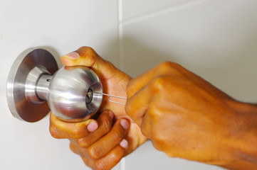 Closeup hands of locksmith using pick tools to open locked door