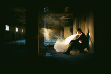 man in a plaid shirt and jeans, smokes an electronic cigarette, blowing smoke and steam from the vaporization a mechanical device. fashionable hobby, alternative to smoking cigarettes, glycerin clouds