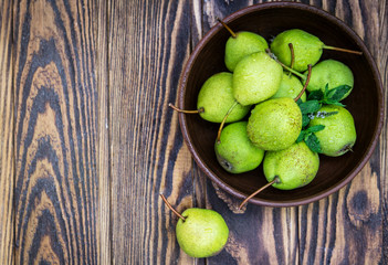 Pears with mint in a bowl on the wooden table