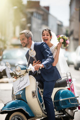  Newlyweds having fun on a decorated vintage scooter