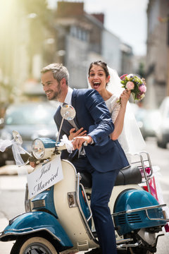 Newlyweds having fun on a decorated vintage scooter