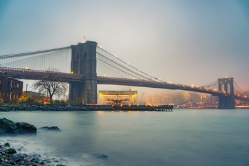 Fototapeta na wymiar Brooklyn bridge and Manhattan at foggy evening, New York City