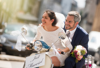 Newlyweds having fun on a decorated vintage scooter