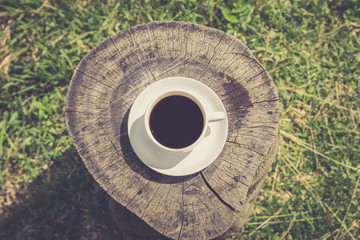 Retro style or Vintage Style, Black Coffee cup Put on a stump or wood table in the garden sunny morning.
