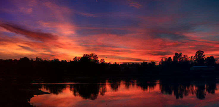 A dramatic sunset reflected in water at dusk over the river Oder, on the German-Polish border, the view from the Polish town of Slubice looking towards German town of Frankfurt (Oder) 