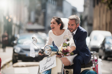  Newlyweds having fun on a decorated vintage scooter