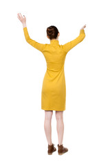 back view of dancing young beautiful  woman in dress. girl  watching. Rear view people collection.  backside view of person.  Isolated over white background. Girl in mustard strict dress dancing