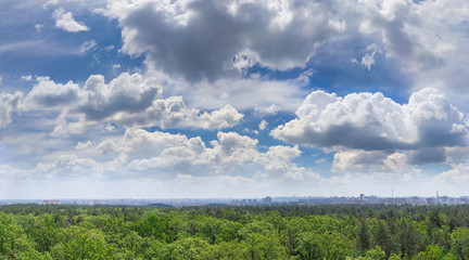 Obraz na płótnie Canvas Sky with cumulus clouds over forest and modern city