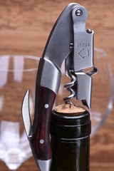 Bottle of wine with corkscrew, closeup