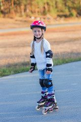 Joyful girl rollerblading in protecting the walk in the park on a summer evening.